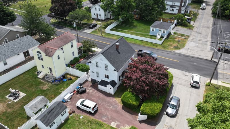 White house with a dark shingle roof on a corner lot