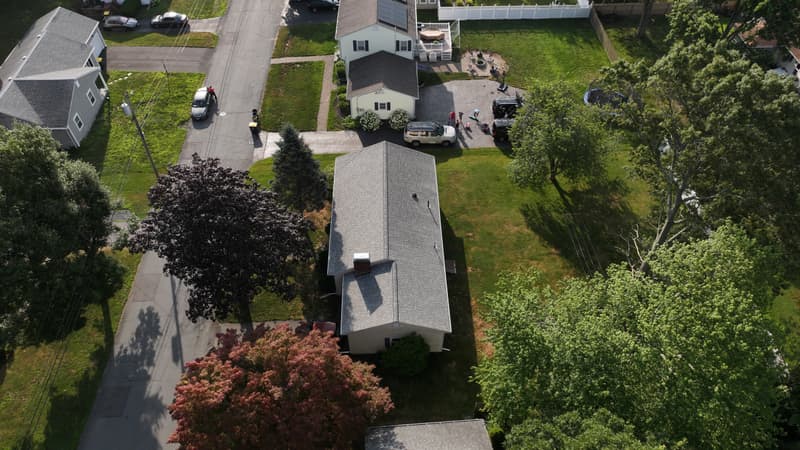 Long house with a light gray shingle roof seen from above
