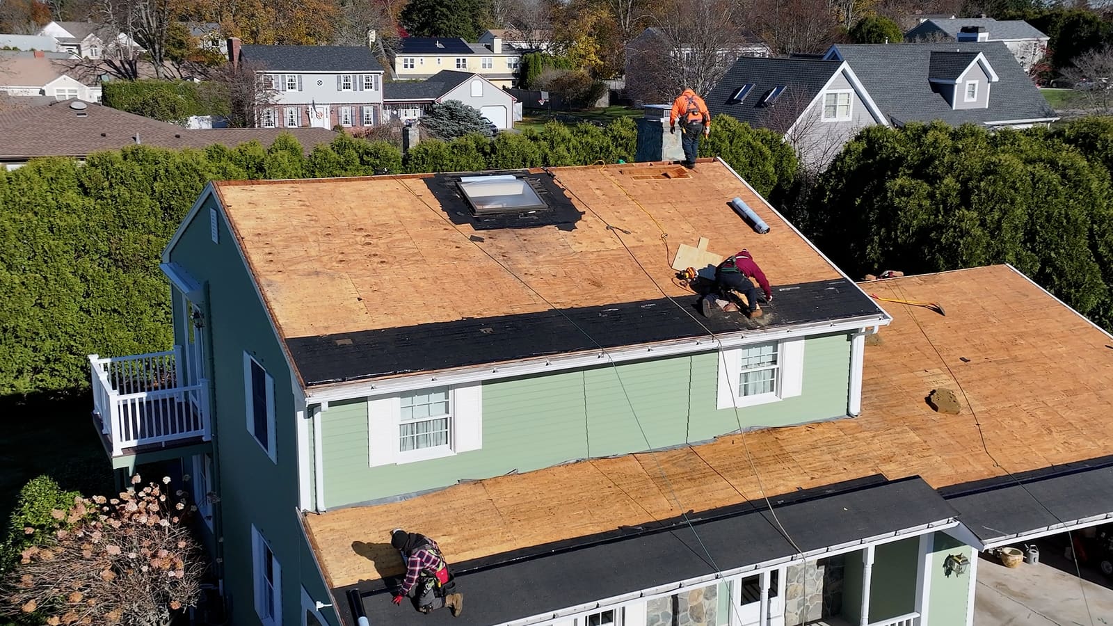 Roofing crew working on bare plywood roof decking during a re-roof