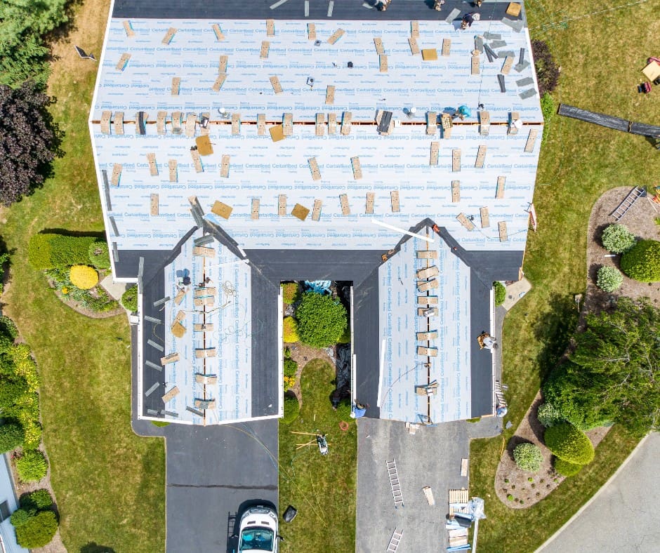 Roof deck covered in underlayment with bundles of shingles laid out, seen from above