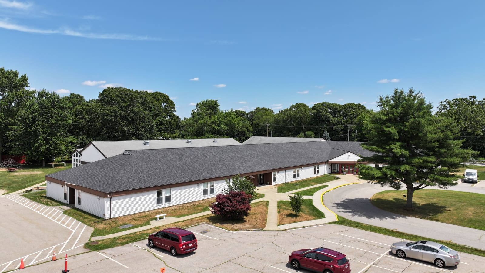 Large single-story building with a new dark shingle roof and a parking lot in front
