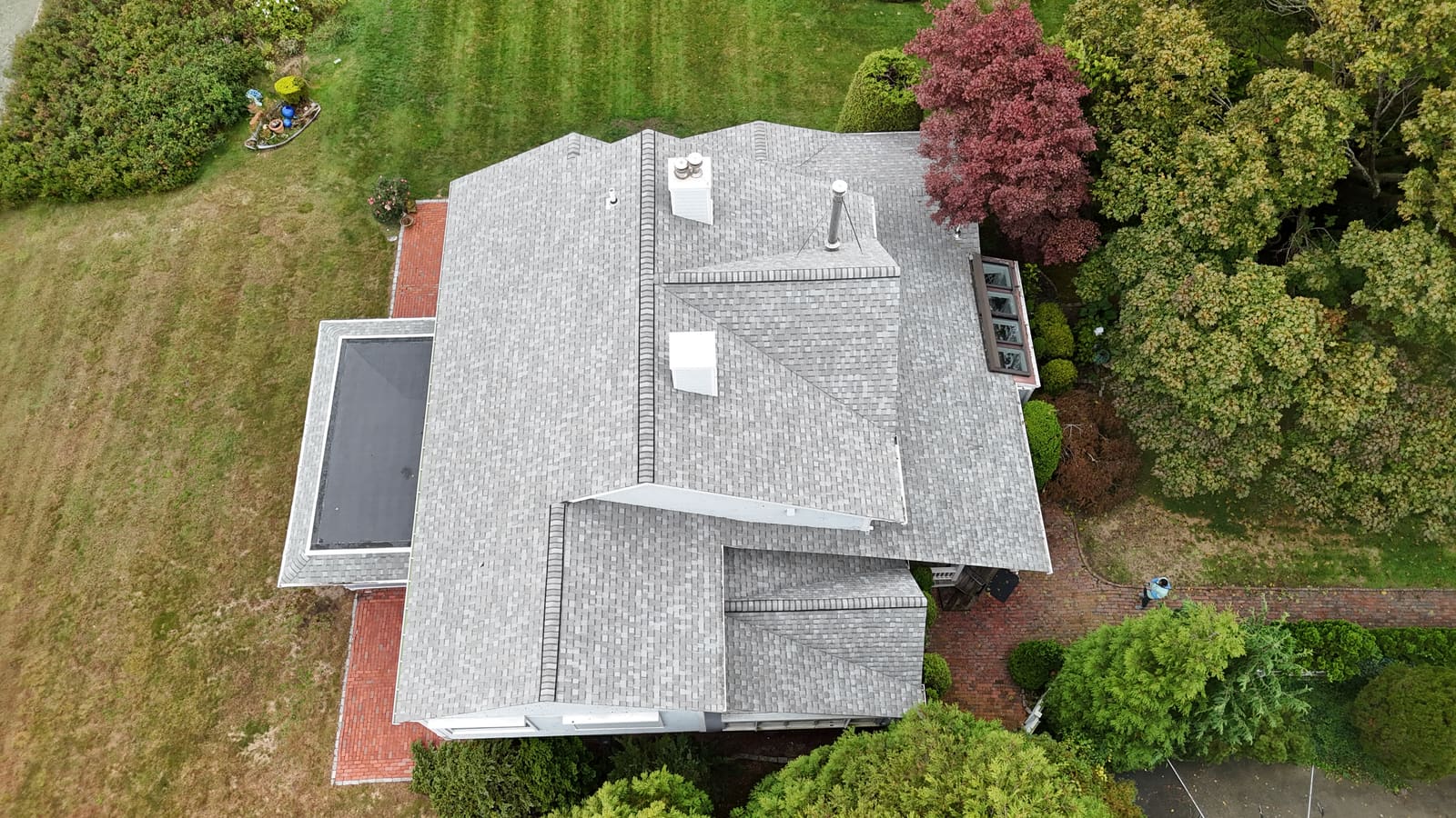 House roof seen from above with a black flat membrane section beside the shingled slopes